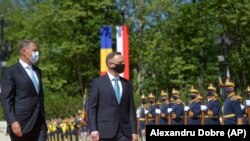 Presiden Polandia Andrzej Duda (kanan) menginspeksi pasukan kehormatan bersama Presiden Romania Klaus Iohannis dalam upacara penyambutan di istana kepresidenan Cotroceni di Bukares, Romania, Senin, 10 Mei 2021. (Foto: Alexandru Dobre/AP)