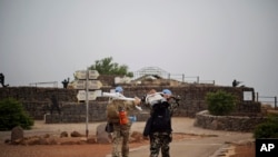 U.N. officers walk with equipment to observe areas in Syria's Quneitra province, at an observation point on Mount Bental in the Israeli-controlled Golan Heights, Monday, June 22, 2015.