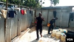 Baba Awolu is attends to a man who wants to use his local toilet and washroom facility "Gidan Wanka" in Jahi Abuja, Nov. 18, 2019. (Timothy Obiezu/VOA)