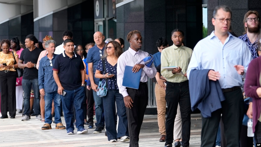 Personas esperan en fila para asistir a una feria de empleo, el jueves 29 de agosto de 2024, en Sunrise, Florida.