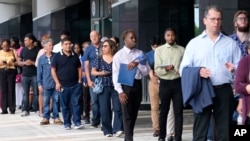 Personas esperan en fila para asistir a una feria de empleo, el jueves 29 de agosto de 2024, en Sunrise, Florida.