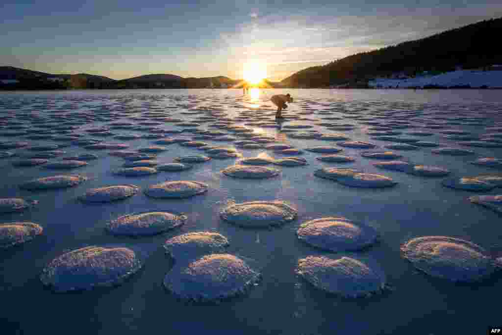 A skater observes pancakes snow on the frozen Lake des Rousses in Les Rousses, central-eastern France, Jan. 1, 2025.&nbsp;This phenomenon forms when slushy ice in water clumps into round, pancake-like shapes due to waves or currents.