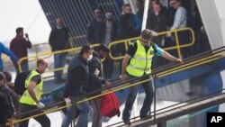 Officers from the European Union’s border protection agency, Frontex, lead a migrant as they get in a ferry in the port of Mytilini, Lesbos island , Greece, April 8, 2016. 