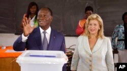 Presiden Pantai Gading Alassane Ouattara (kiri) setelah memberikan suaranya di sebuah TPS bersama istrinya Dominique Ouattara, di Abidjan (25/10). (AP/Schalk van Zuydam)