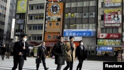 People cross a street in a business district in Tokyo, Japan.