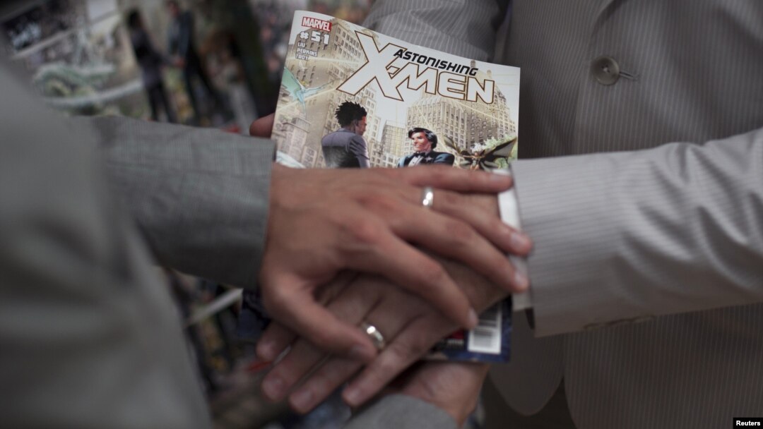 Jason Welker (L) and Scott Everhart pose with their bands on top of an X-Men comic book after exchanging wedding vows at a comic book retail shop in Manhattan, New York June 20, 2012.