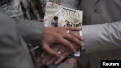 Jason Welker (L) and Scott Everhart pose with their bands on top of an X-Men comic book after exchanging wedding vows at a comic book retail shop in Manhattan, New York June 20, 2012. 