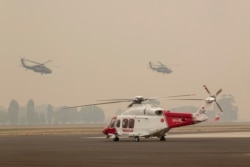 Two Australian Army Black Hawk helicopters fly through smoke at RAAF Base East Sale during bushfire relief efforts, Jan. 3, 2020.
