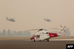 Two Australian Army Black Hawk helicopters fly through smoke at RAAF Base East Sale during bushfire relief efforts, Jan. 3, 2020.