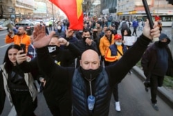FILE - People protesting the COVID-19 pandemic restrictions march in downtown Bucharest, Romania, March 29, 2021.