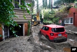 A vehicle is dug out of the mud after a storm Feb. 14, 2025, in Sierra Madre, Calif.