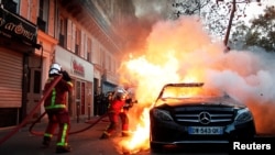 Firefighters extinguish blazes during a demonstration against legislation that rights groups say would make it a crime to circulate an image of a police officer's face and would infringe on journalists' freedom in France, in Paris, Nov. 28, 2020.