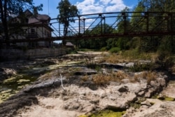 FILE - A picture taken on July 31, 2020, in Maisons-du-Bois-Lievremont, eastern France, shows a house next to a bridge crossing over the dry Doubs river as a heatwave hits France.