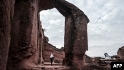 FILE - An Ethiopian Orthodox devotee walks near the rock-hewn church of Saint Mercurius in Lalibela, Ethiopia, March 7, 2019. 