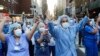 FILE - Nurses and medical workers react as police officers and pedestrians cheer them outside Lenox Hill Hospital Wednesday, April 15, 2020, in New York.