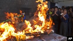 Tibetan exiles pray next to the burning funeral pyre of 27-year-old Jamphel Yeshi, who passed away Wednesday morning two days after he immolated himself in New Delhi, in Dharmsala, India, March 30, 2012.