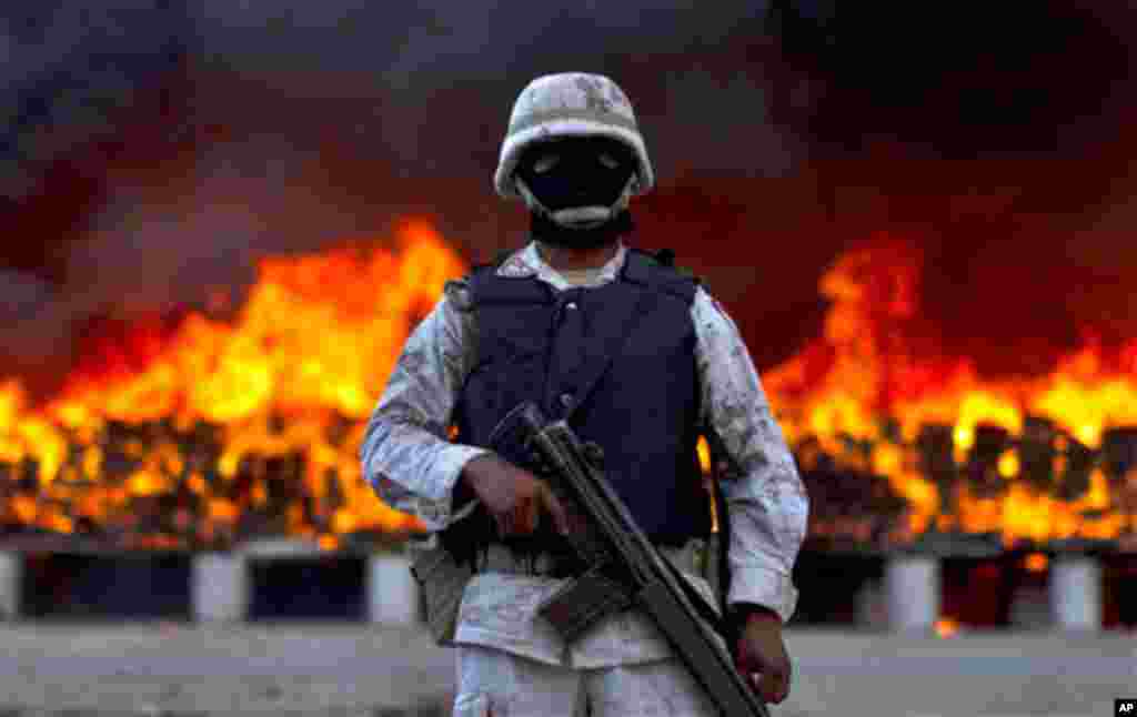 A soldier guards next to packages of marijuana that are being incinerated in Tijuana, Mexico, Wednesday, Oct. 20, 2010. On a conjoined operation with the army, local and state police seized 134 tons of U.S.-bound marijuana Monday, by far the biggest drug