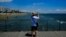FILE - A tourist takes photos the view from the sea in southeast coast city of Larnaca in the eastern Mediterranean island of Cyprus, June 1, 2021. 