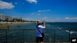 A tourist takes photos the view from the sea in southeast coast city of Larnaca in the eastern Mediterranean island of Cyprus, June 1, 2021. 