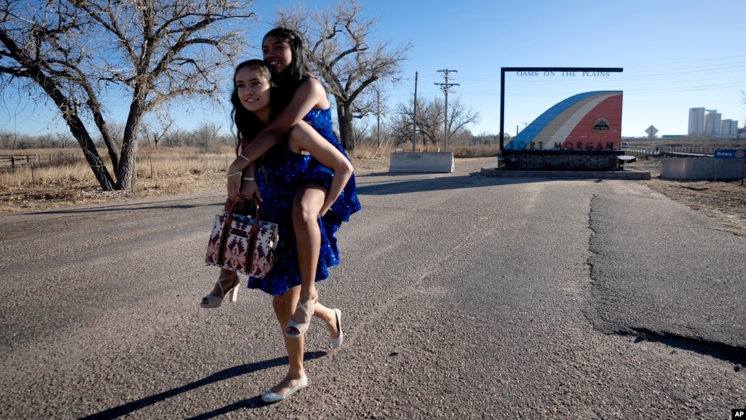 Dos migrantes adolescentes participantes de una fiesta de Quinceañera posan para los fotógrafos en el puente Rainbow de Fort Morgan, Colorado, el 16 de diciembre de 2023.
