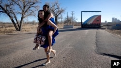 Dos migrantes adolescentes participantes de una fiesta de Quinceañera posan para los fotógrafos en el puente Rainbow de Fort Morgan, Colorado, el 16 de diciembre de 2023.