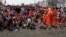 A Cambodian Buddhist monk, right, talks on a loud speaker as garment workers sit behind barbed wire set up by police near the Council of Ministers building during a rally in Phnom Penh, Cambodia, Monday, Dec. 30, 2013. The workers are demanding a raise in their monthly salary from US $160 to $80. (AP Photo/Heng Sinith)