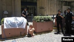 A girl sits beside a sign with the image of a soldier, during a protest by Argentine Falklands War veterans outside the British Embassy in Buenos Aires, January 3, 2013.