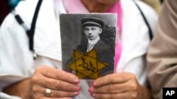 FILE - A woman holds a photo of her father killed at the Nazi death camp Sachsenhausen as she attends a rally against anti-Semitism near the Brandenburg Gate in Berlin, Sunday, Sept. 14, 2014.