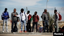 FILE - African migrants stand outside the Holot detention center in Israel's Negev desert, March 13, 2018. 