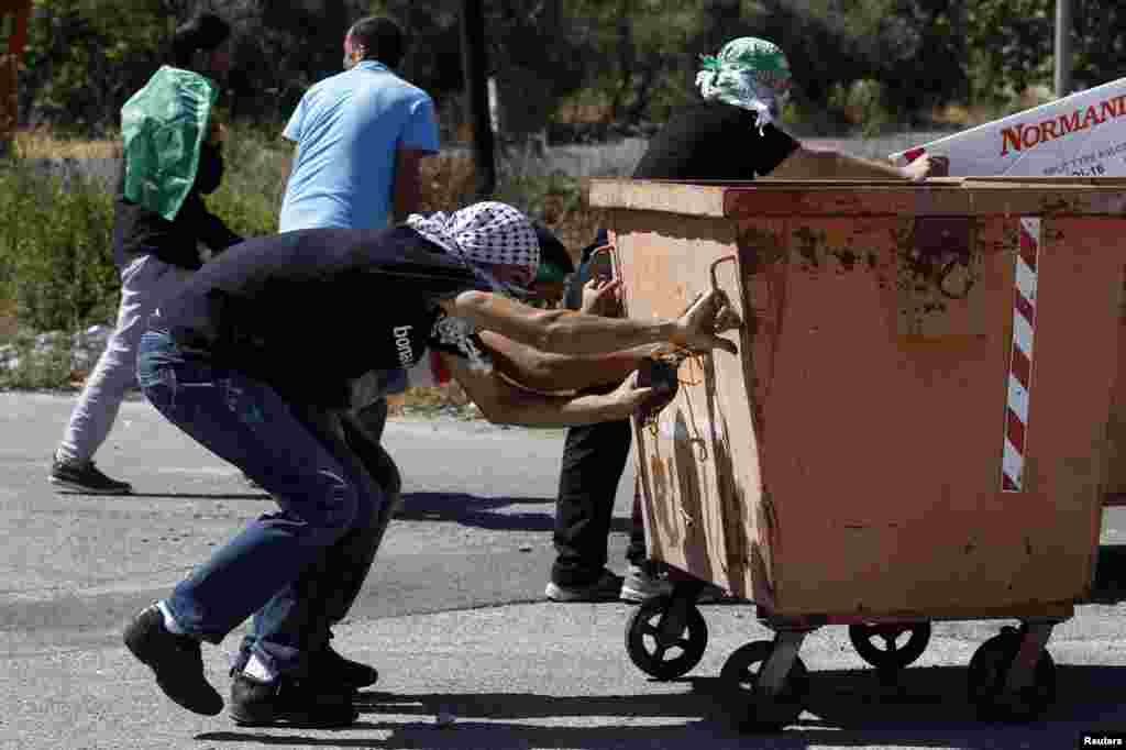 Waandamani wa Palestina wajificha nyuma ya pipa la taka wakati wa mapambano na wanajeshi wa Israeli dhidi ya uvamizi wa Israel huko Gaza, karibu na makazi ya ayahudi ya Bet El, karibu na mji wa Ramallah, Ukingo wa Magharibi, July 25, 2014.&nbsp;