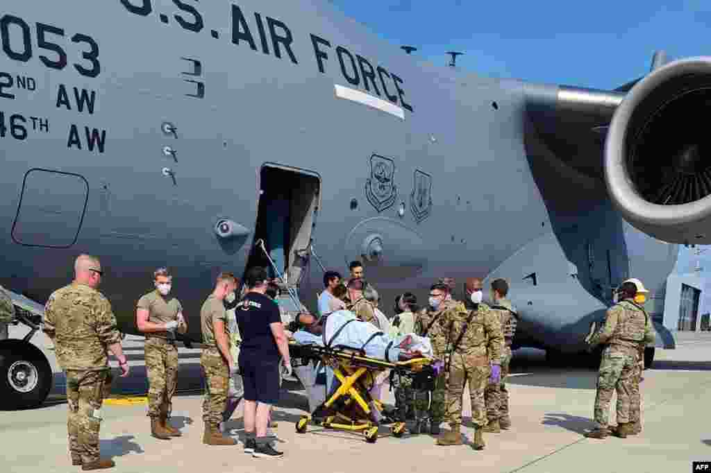 Medical support personnel from the 86th Medical Group help an Afghan mother and family off a U.S. Air Force C-17 moments after she delivered a child aboard the aircraft upon landing at Ramstein Air Base, Germany, Aug. 21, 2021. (Credit: U.S. Air Force)