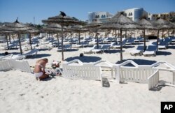 FILE - A young woman lays a flowers at the scene of a shooting in Sousse, Tunisia, June 27, 2015.