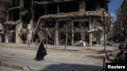 2026년 4월 20일, 레바논 베이루트 남부 외곽에서 한 여성이 이스라엘과 레바논 간의 10일간 휴전 속에 파손된 건물들 사이를 지나가고 있다.