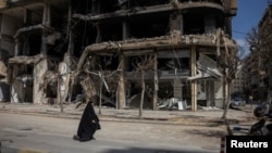 2026년 4월 20일, 레바논 베이루트 남부 외곽에서 한 여성이 이스라엘과 레바논 간의 10일간 휴전 속에 파손된 건물들 사이를 지나가고 있다.