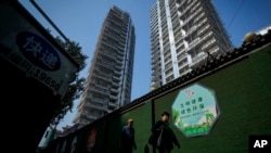 Residents walk by a luxury housing construction site in Beijing, Sept. 24, 2024.