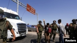 Agentes de la policía sacan a mujer mientras inmigrantes indocumentados bloquean una carretera en la frontera chilena y peruana mientras permanecen atrapados en Chile, luego de que Perú se negara a abrir sus fronteras el 23 de abril de 2023.