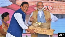 India's Prime Minister Narendra Modi (R) plays traditional drums as the chief minister of Assam state Himanta Biswa Sarma watches during an election campaign rally at Nalbari in Assam state on April 17, 2024, ahead of the country's upcoming general electi