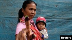 Seorang ibu sambil menggendong bayinya menunjukkan jarinya usai mencoblos di Bondowoso, Jawa Timur dalam pemilu 2014 (Foto Reuters/Sigit Pamungkas).