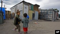 Children play outside a house in a township on the outskirts of Cape Town, South Africa, 27 May 2010