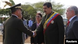 Venezuela's President Nicolas Maduro, right, shakes hands with Venezuela's Defense Minister Vladimir Padrino Lopez as he arrives to commemorate the Battle of San Felix, April 11, 2017.