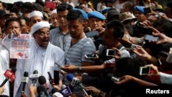 Pemimpin Front Pembela Islam (FPI), Muhammad Rizieq Shihab, berbicara kepada para wartawan di Mabes Polri menyusul pemanggilannya. Rizieq saat itu dipanggil polisi untuk ditanyai seputar klaimnya bahwa lembaran uang kertas baru bergambar simbol mirip lambang komunis palu dan arit, yang dilarang di Indonesia, Jakarta, 23 Januari 2018.