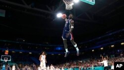 Anthony Edwards, de Estados Unidos, en el centro, realiza una volcada mientras Stevie Thompson Jr., de Puerto Rico, observa durante un partido de baloncesto masculino en los Juegos Olímpicos de Verano de 2024, el sábado 3 de agosto de 2024, en Villeneuve-d'Ascq, Francia.