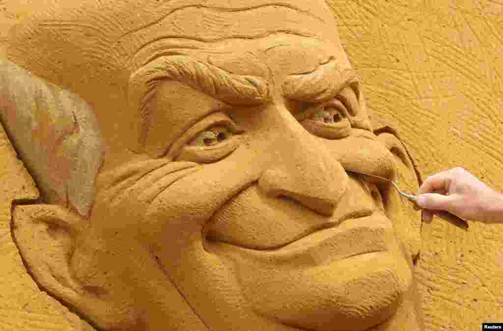 A sand carver works on a sculpture depicting French actor Louis de Funes, during the Sand Sculpture Festival &quot;Dreams&quot; in Ostend, Belgium.