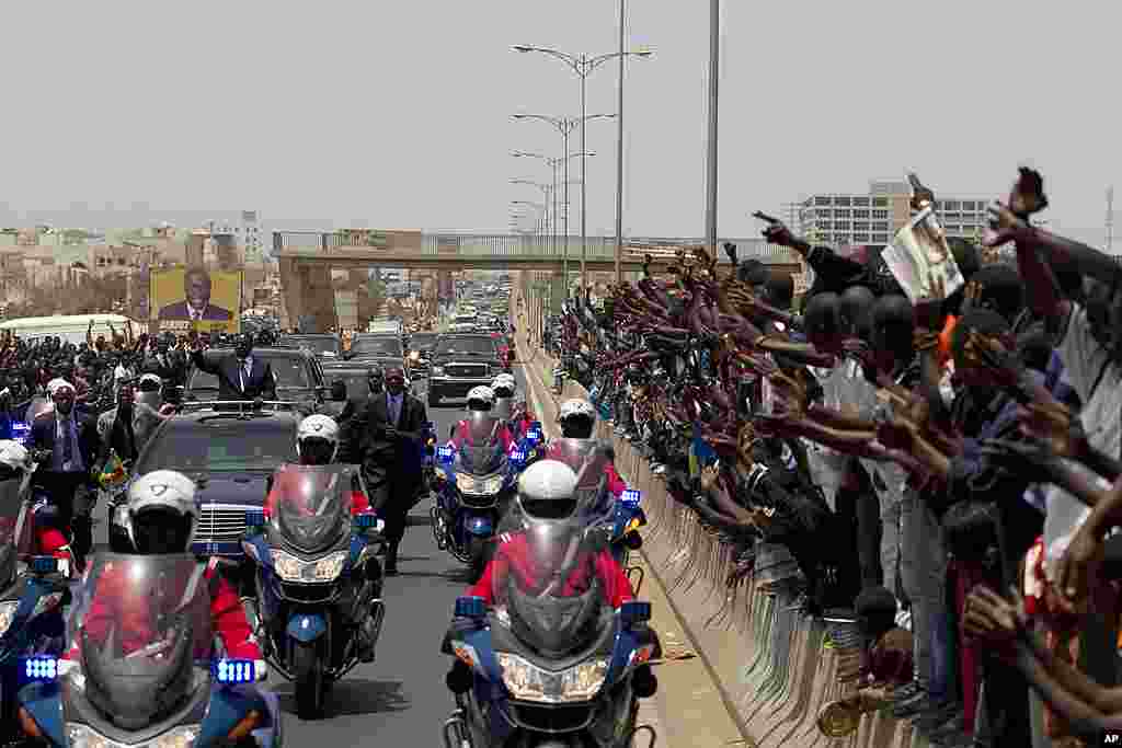 Senegal's newly inaugurated President Macky Sall waves to supporters from his convoy as he travels to the presidential palace to take up residence, in Dakar. (AP)