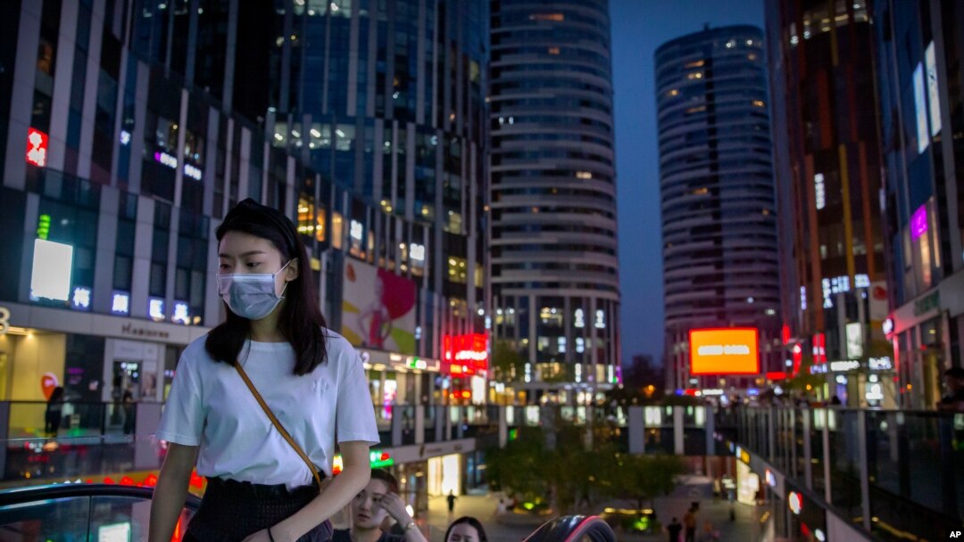 People wearing face masks to protect against the coronavirus ride an escalator at a shopping and office complex in Beijing, July 16, 2020. 