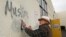 Tom Garing cleans up racist graffiti painted on the side of a mosque in what officials are calling an apparent hate crime, Feb. 1, 2017, in Roseville, Calif. The Tarbiya Institute was spray-painted with a dozen obscene and racist slurs. Garing, a retiree who lives in the area and is not a member of the mosque, volunteered to help clean up.