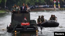 (L-R) Indonesia Military Chief Gatot Nurmantyo, Indonesia President Joko Widodo, and Indonesia Police Chief Tito Karnavian stand on a military amphibious vehicle Anoa 2 while crossing a lake at a military headquarters in Jakarta, Jan. 16, 2017.