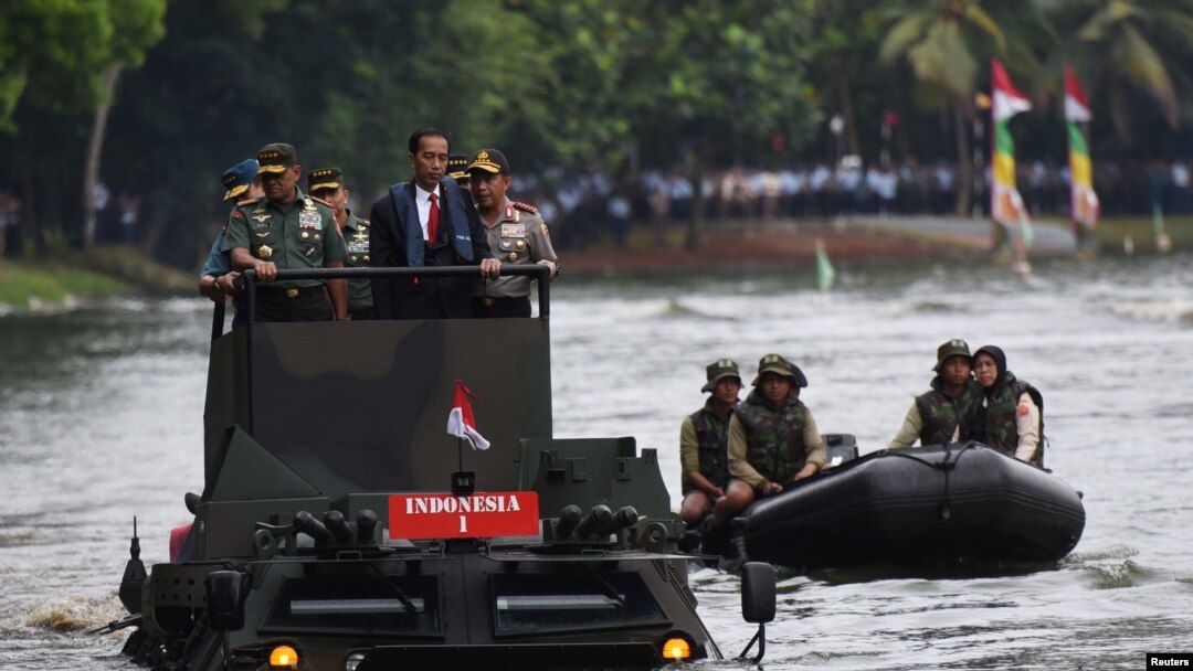 Presiden Joko Widodo, bersama Panglima TNI Jenderal Gatot Nurmantyo (kiri) dan Kapolri Jenderal Tito Karnavian (kanan), menyeberangi danau di Jakarta dengan memakai kendaraan amfibi militer Anoa 2 (16/1). 
