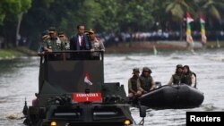 Presiden Joko Widodo, bersama Panglima TNI Jenderal Gatot Nurmantyo (kiri) dan Kapolri Jenderal Tito Karnavian (kanan), menyeberangi danau di Jakarta dengan memakai kendaraan amfibi militer Anoa 2 (16/1). 