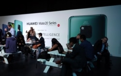 FILE - People attend a Huawei Mate20 smartphone series launch event in London, Britain, Oct. 16, 2018.
